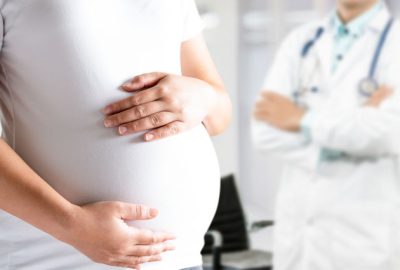 Happy pregnant woman visit gynecologist doctor at hospital or medical clinic for pregnancy consultant. Doctor examine pregnant belly for baby and mother healthcare check up. Gynecology concept.